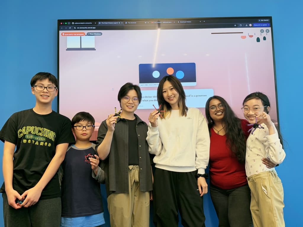 Students and instructors together in front of a student game on the big screen