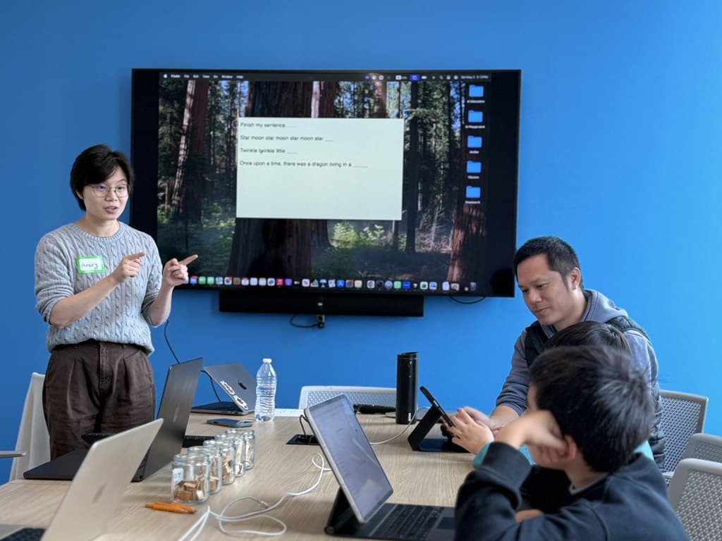 Instructor running a session at the screen while students follow along at the table