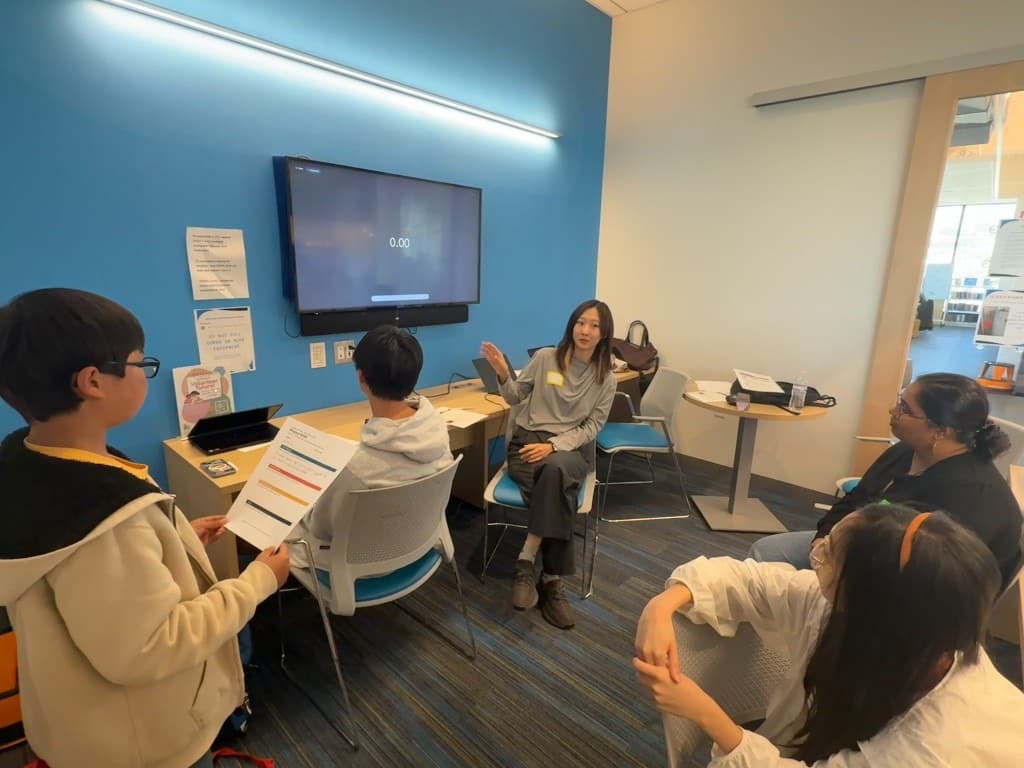 Instructor and students discussing a project brief in a circle