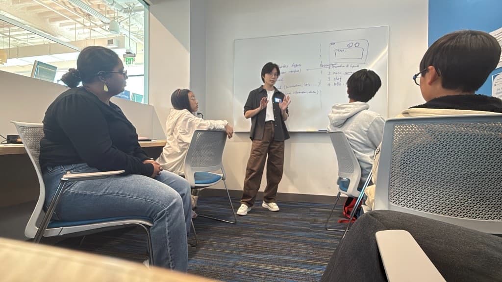 Instructor gesturing while teaching website layers to the group