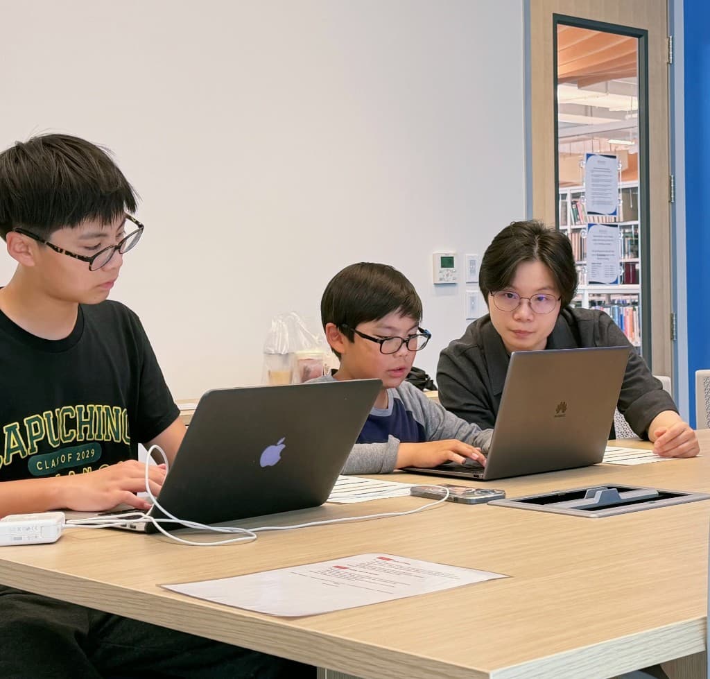 Mentor and two students working together on laptops during Vibe Coding